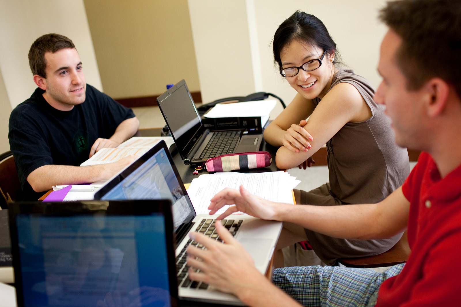 Students at their laptops with papers splayed out on the table beside them