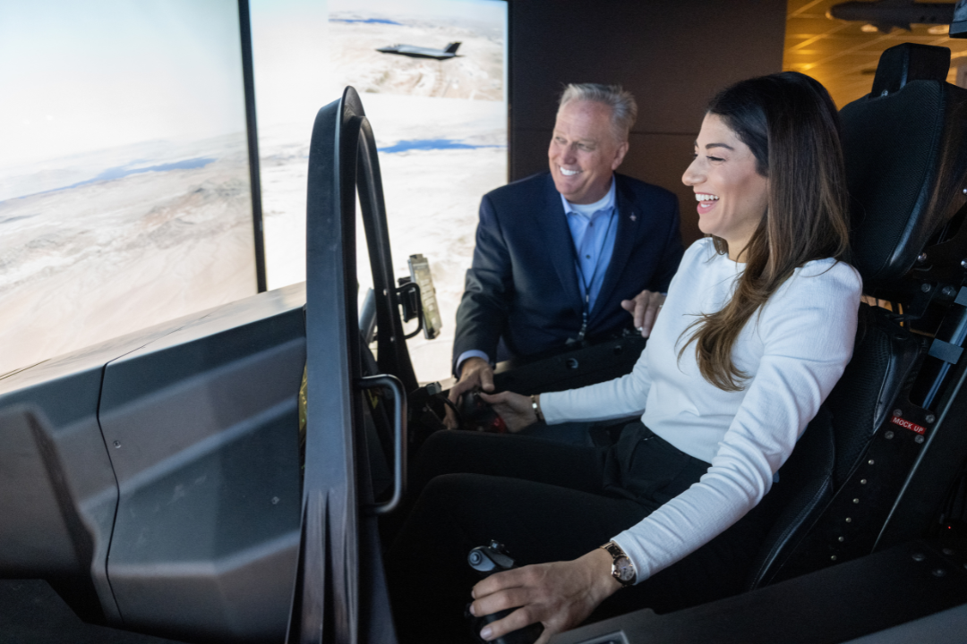 A student learning how to fly the aircraft simulator with an instructor helping her