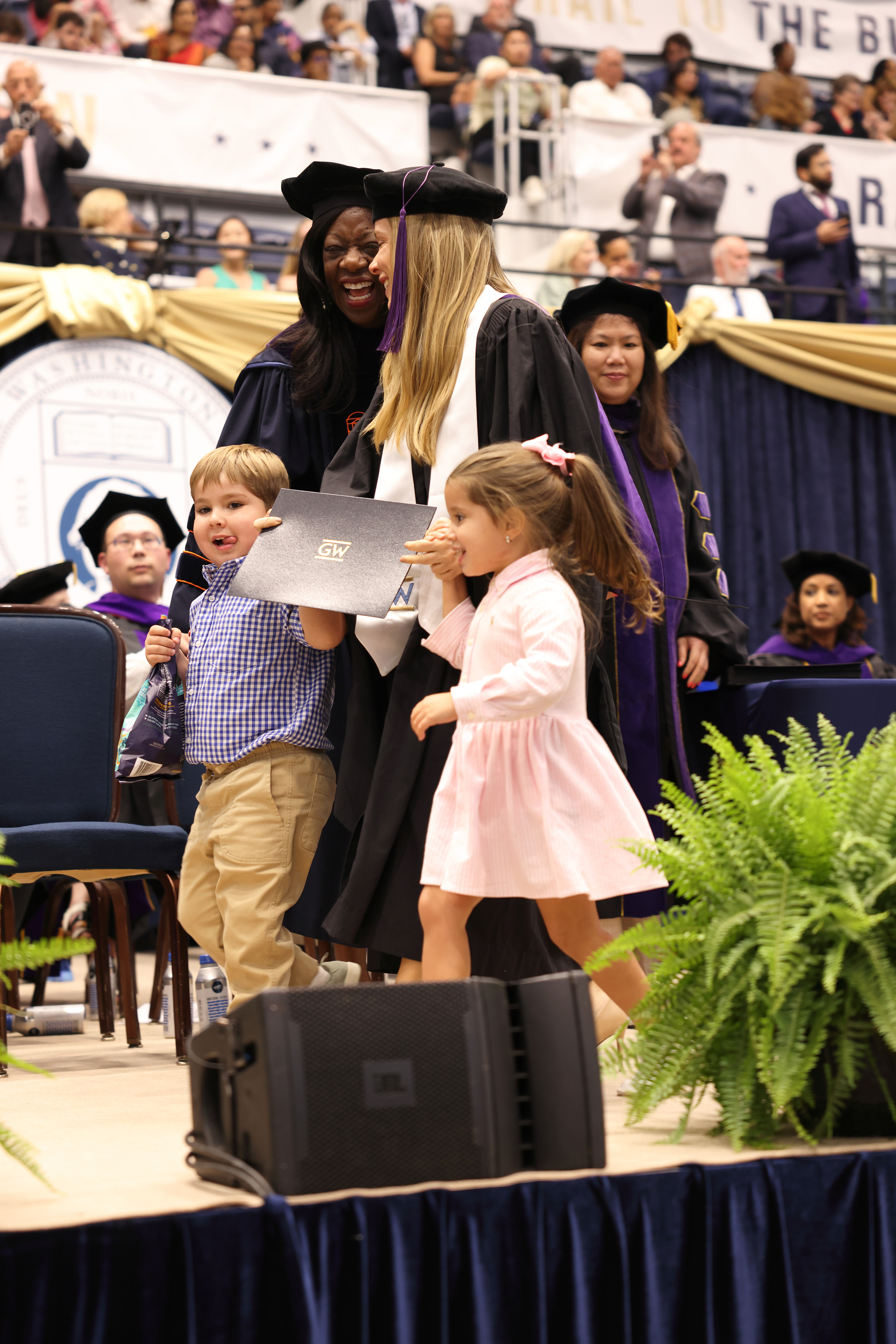 GW Law graduate walking across the stage with her two kids