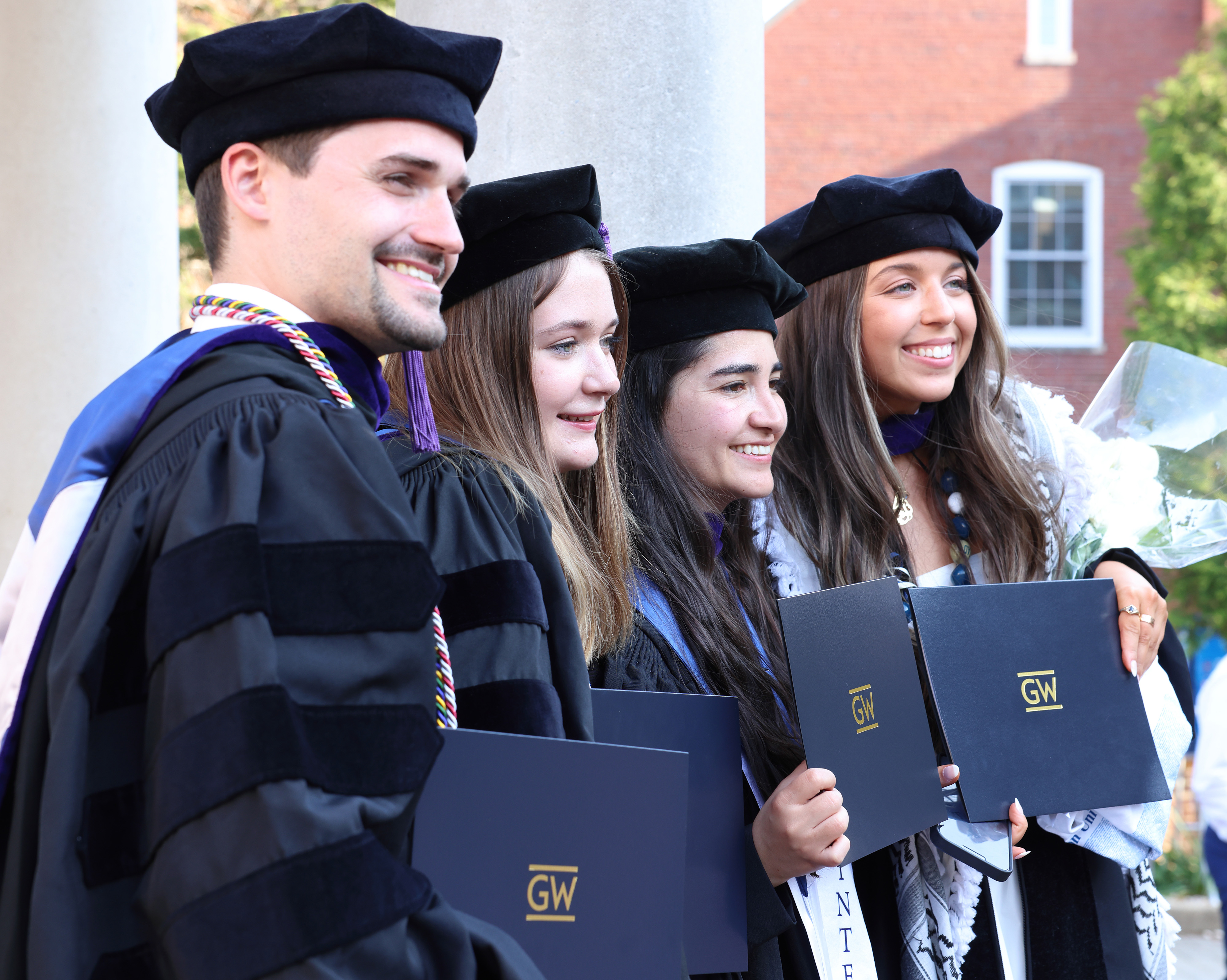 Four graduates smiling with their degrees