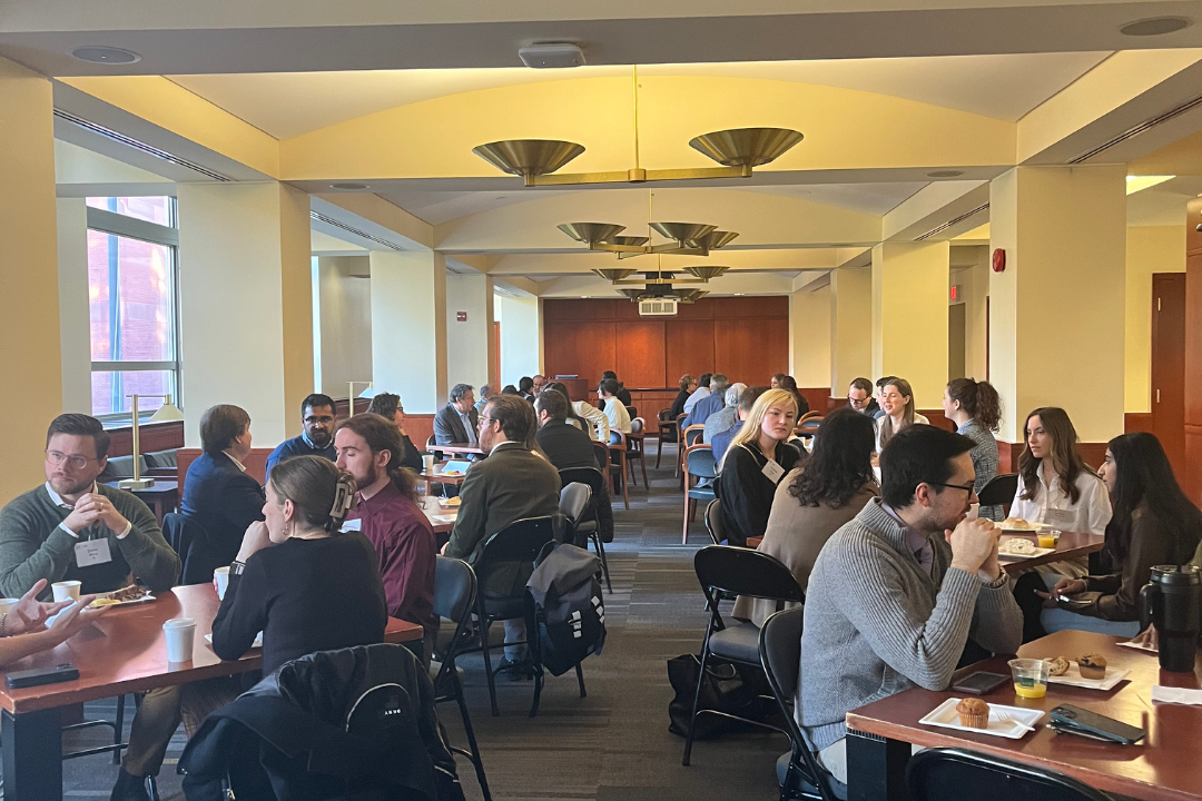 Students and alumni sitting at tables talking and eating pastries