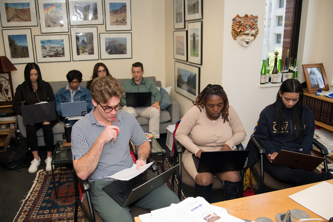 Group of students in a professors office working on laptops