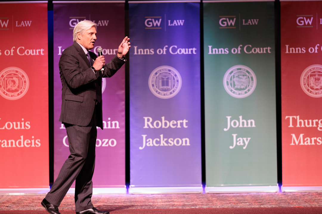 Professor speaking at orientation in front of Inns of Court banners