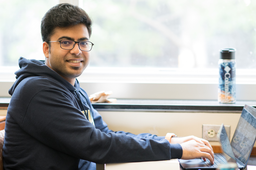 A male student looking at the camera and typing