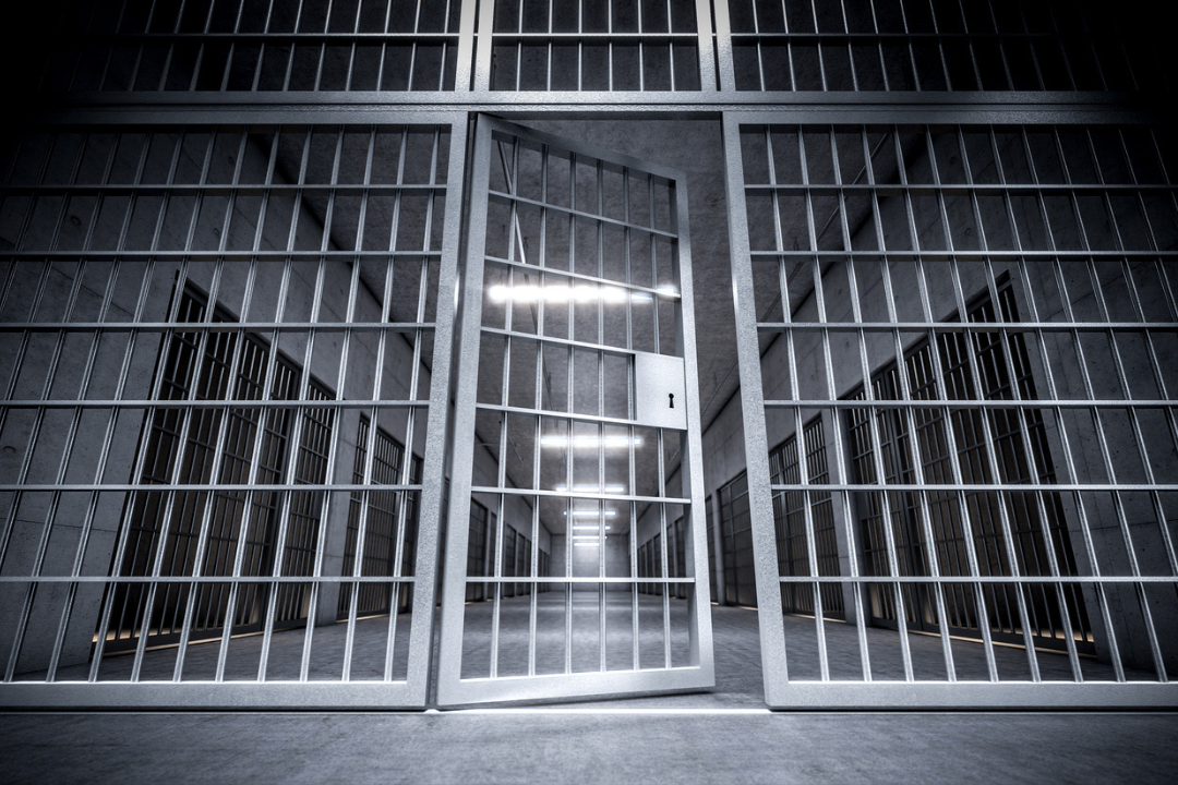 corridor of a prison with bars and open cell door