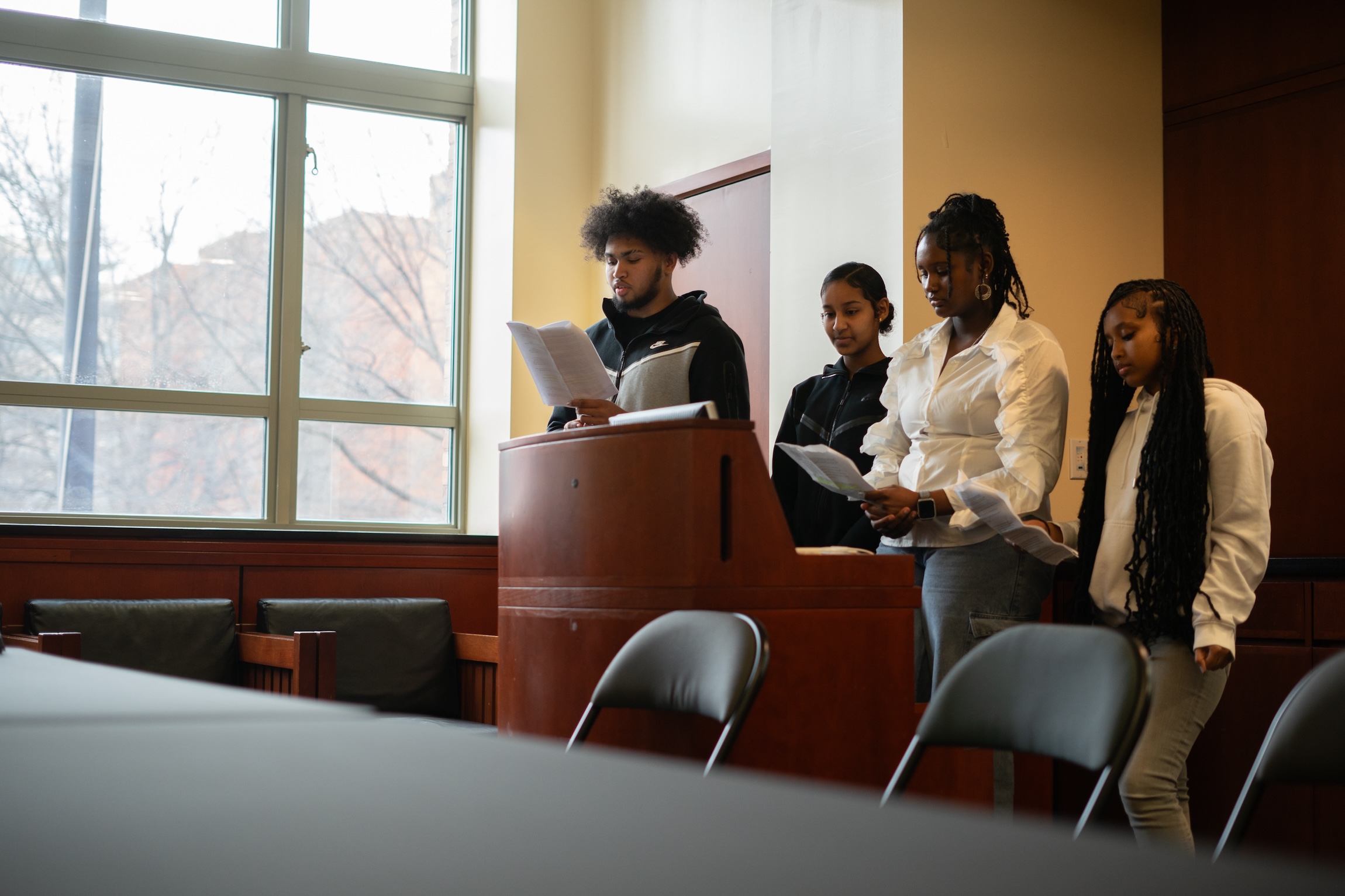 4 students stand behind podium giving a presentation