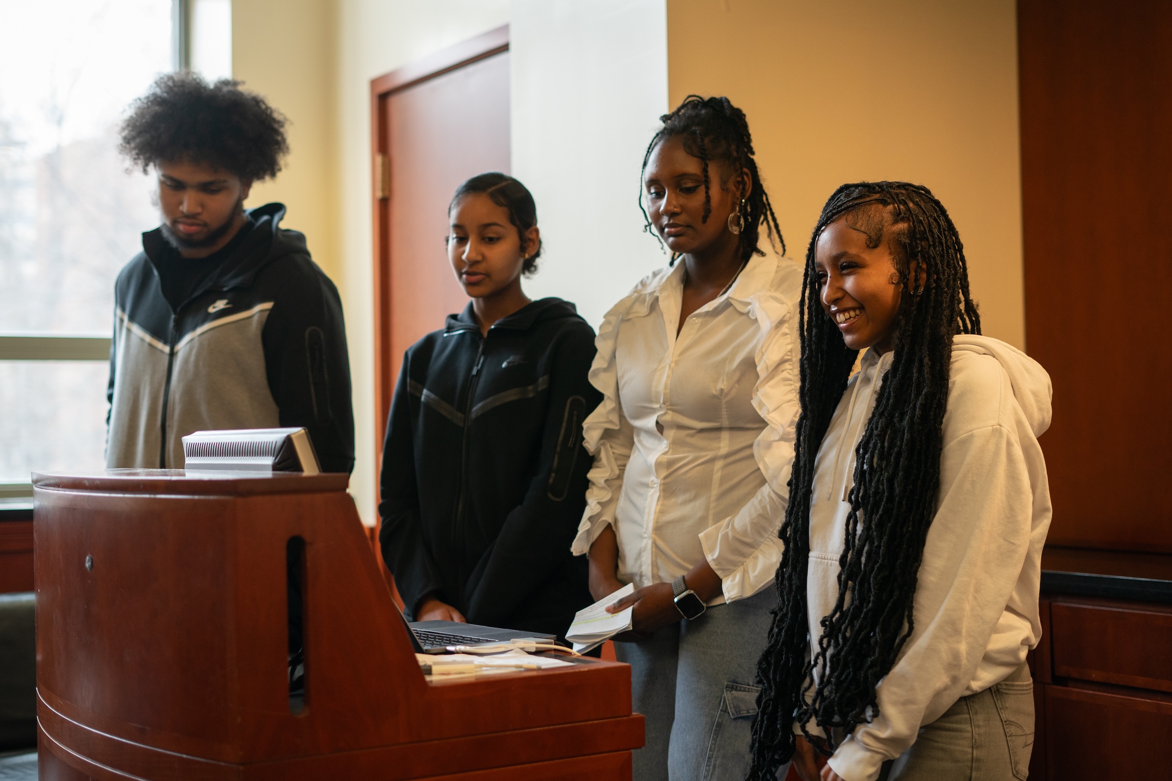 4 students stand behind podium giving a presentation