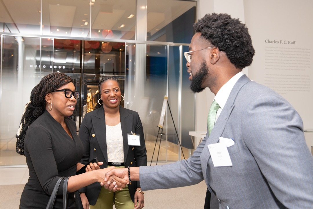 GW Law alumnus shaking hands with two women