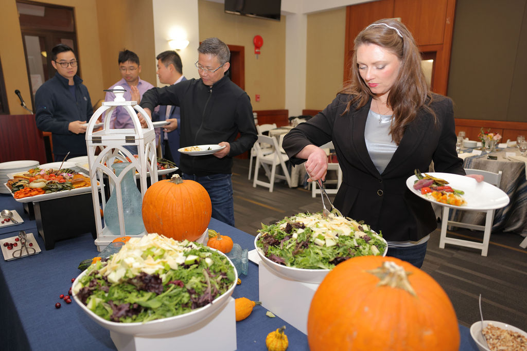 A woman in a black blazer places salad on her plate during the 2024 GW Law Mid Year graduation celebration. 