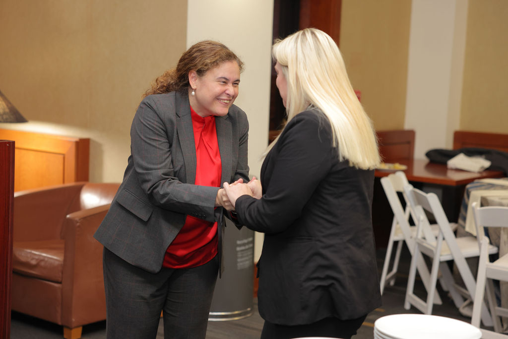 Associate Dean Rosa Celorio shakes a woman's hand during the 2024 MidYear Graduation Luncheon. 