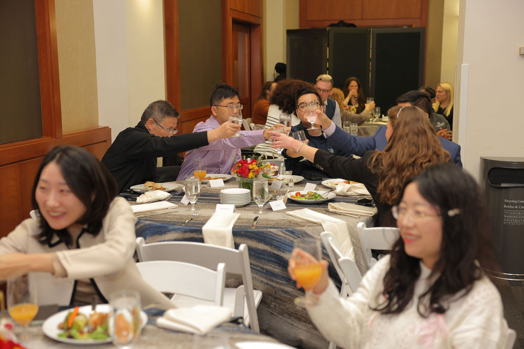 Attendees of the 2024 Mid Year Graduation Luncheon cheers glasses across a table.