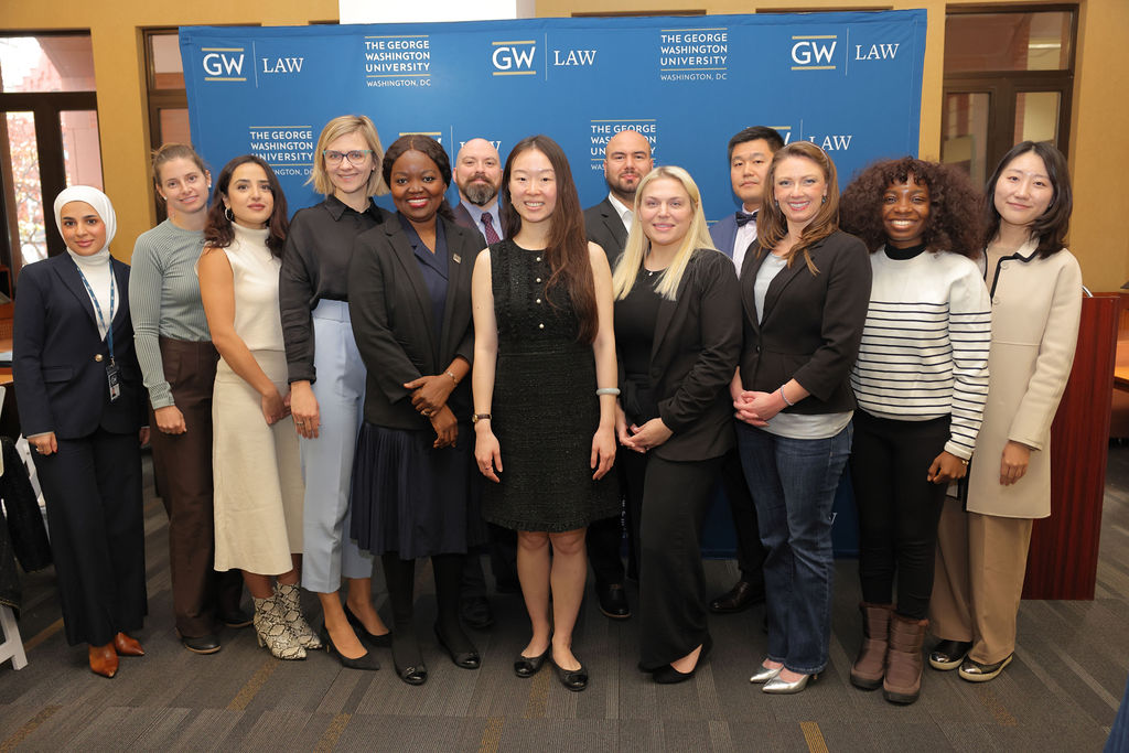 Graduating students pose for a photo in front of a GW Law step and repeat at the 2024 Mid Year Graduation Luncheon. 