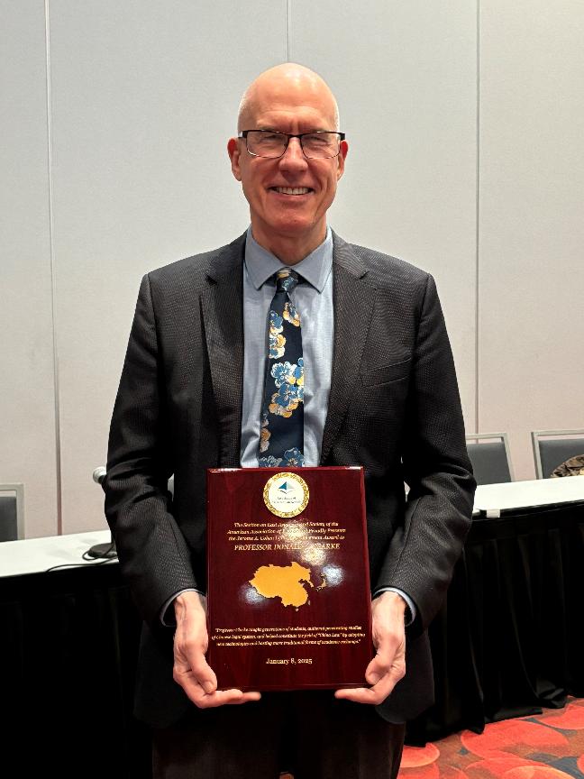 Donald Clarke poses for a photo with a plaque showing his award at the 2025 AALS meeting