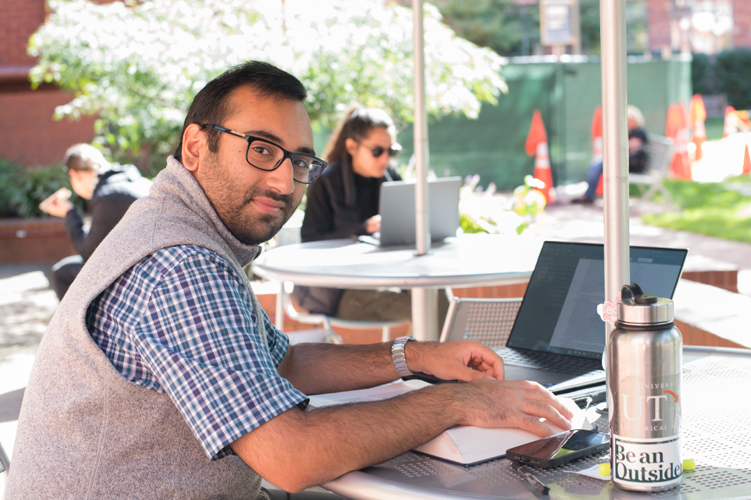 A student working on his laptop in the University Yard.
