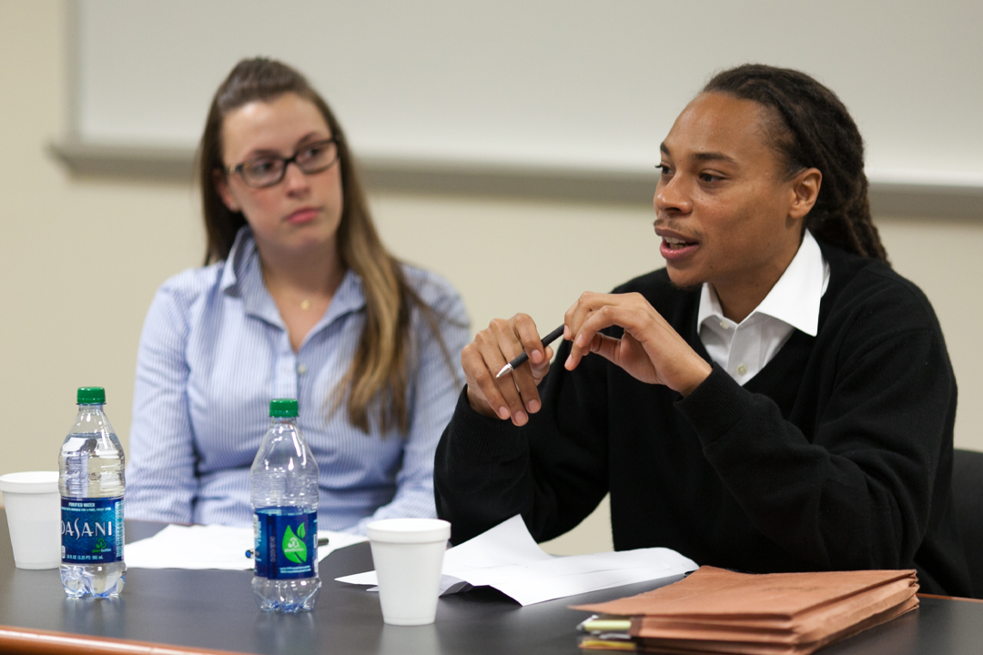 Two students seated at a table, each with a water bottle, sharing a moment of discussion.