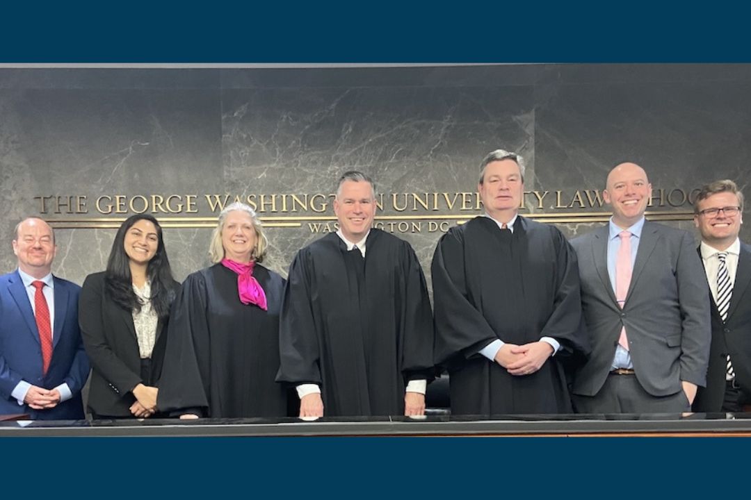 GW Law students and professors pose for a photo in the Burns Moot Court Room