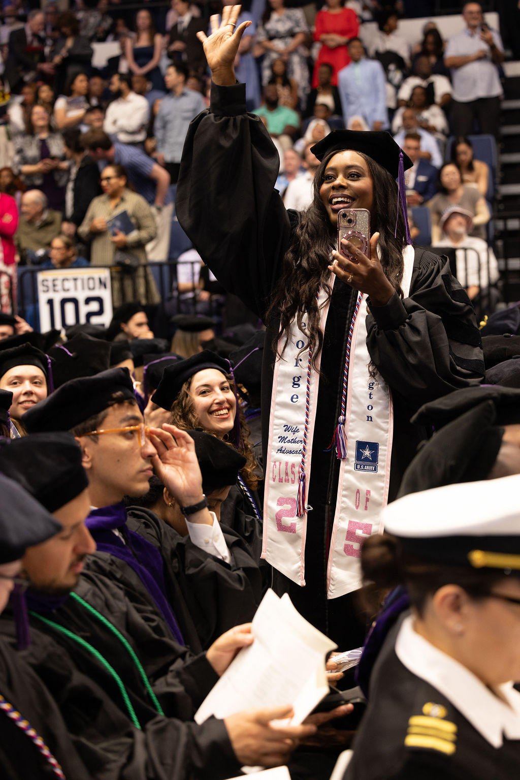 A GW Law graduate waves to the crowd during the 2025 commencement ceremony.