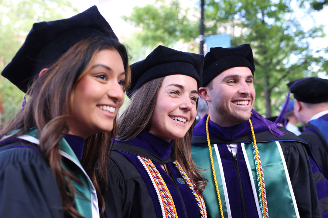 Three graduates posing for a photo in their regalia after commencement.