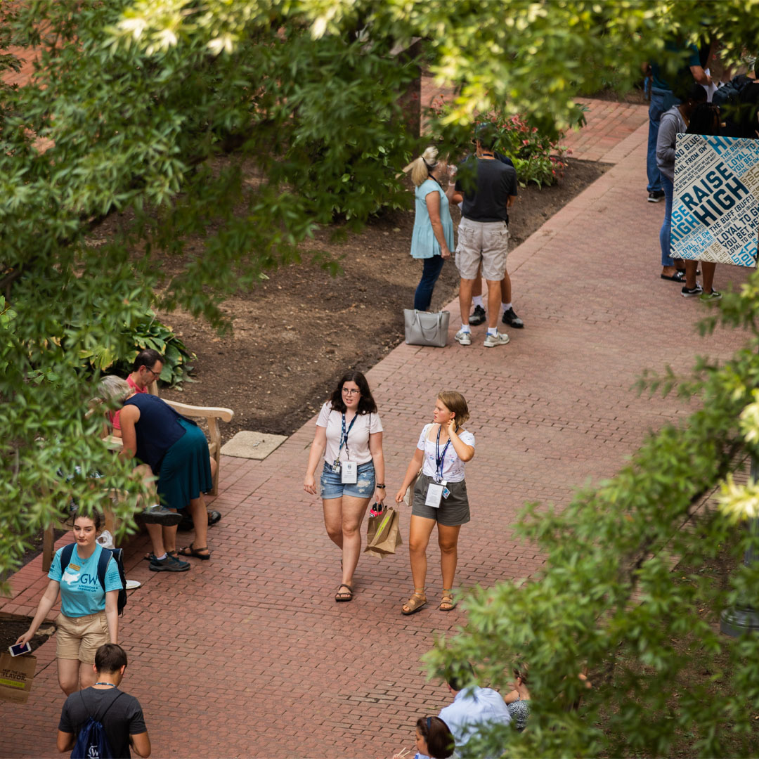 Two girls walking on a crowded sidewalk on campus during orientation