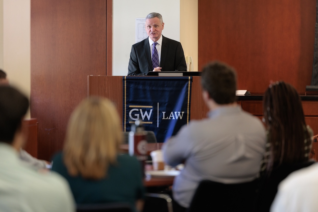 LTG Berger speaks behind a GW Law podium with an audience depicted in the foreground.