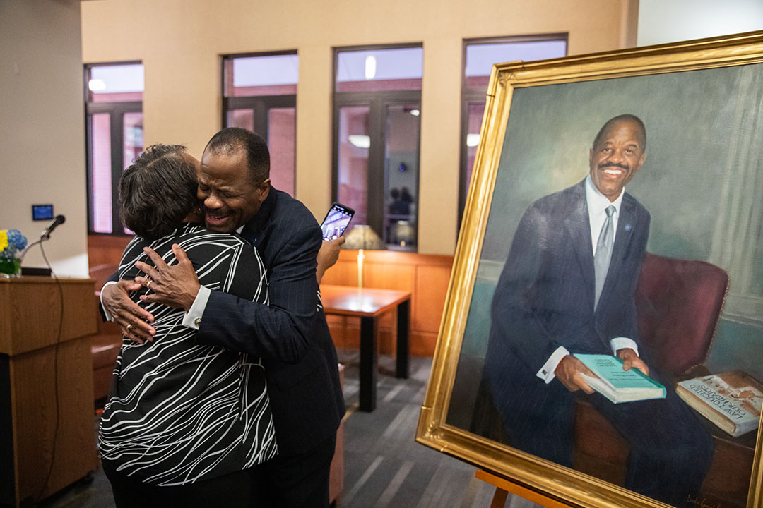 Professor Morant hugs a woman in front of his new portrait.