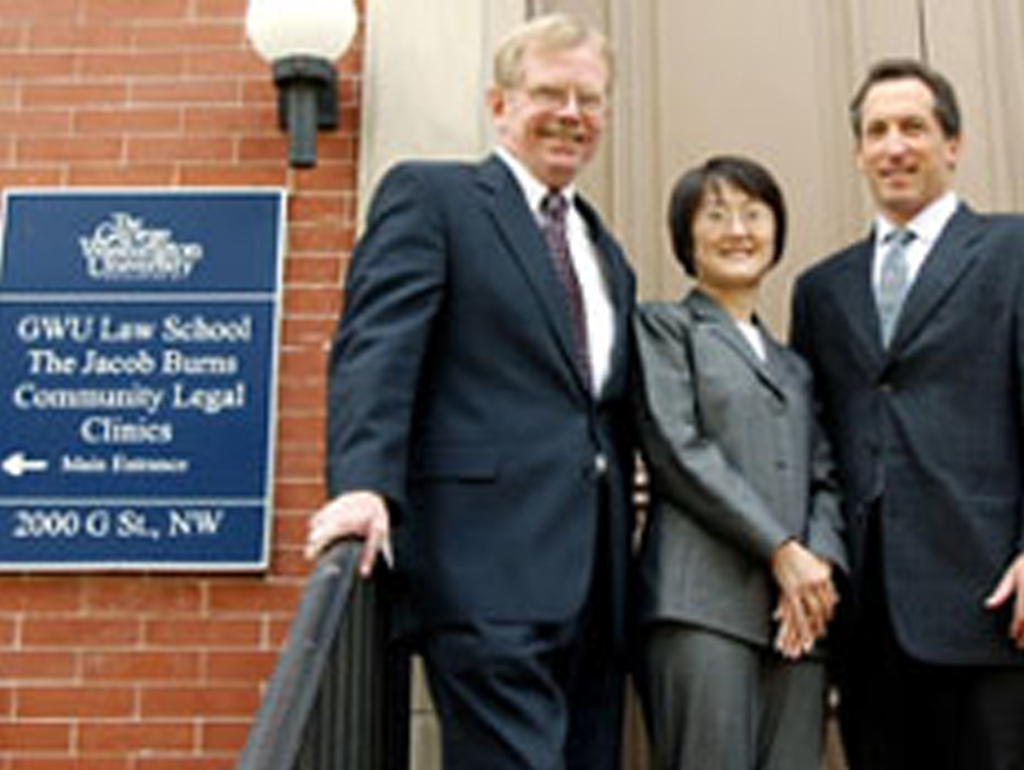 Three Friedman Fellows standing in front of the Clinics building sign