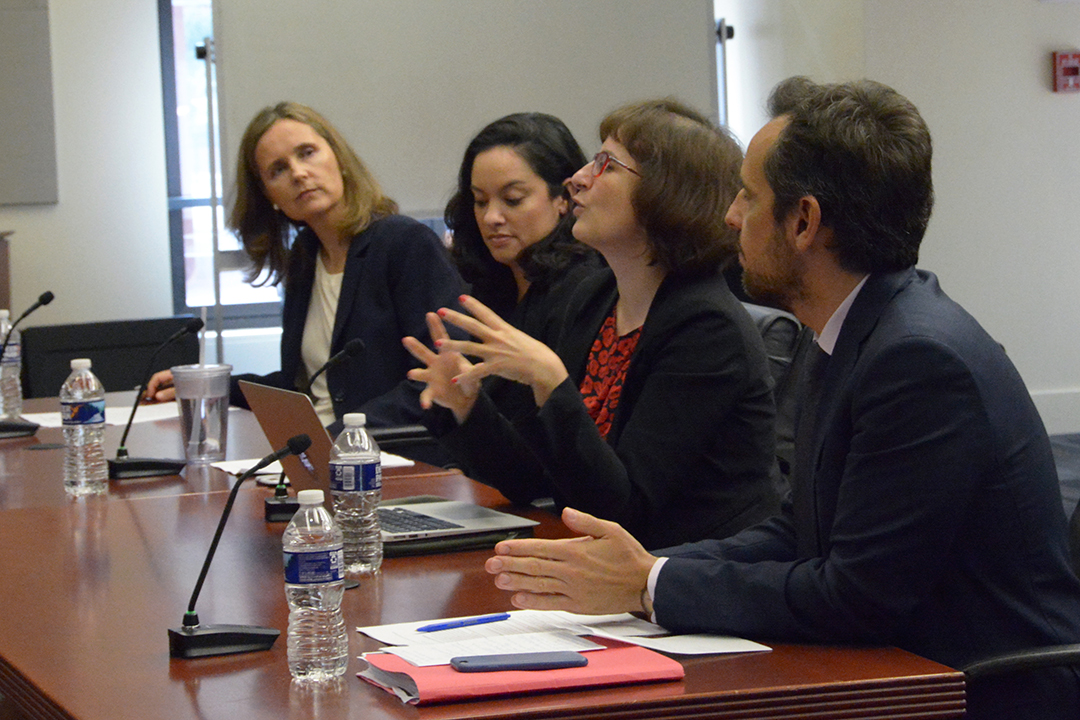 A panel of four sits at a table talking.