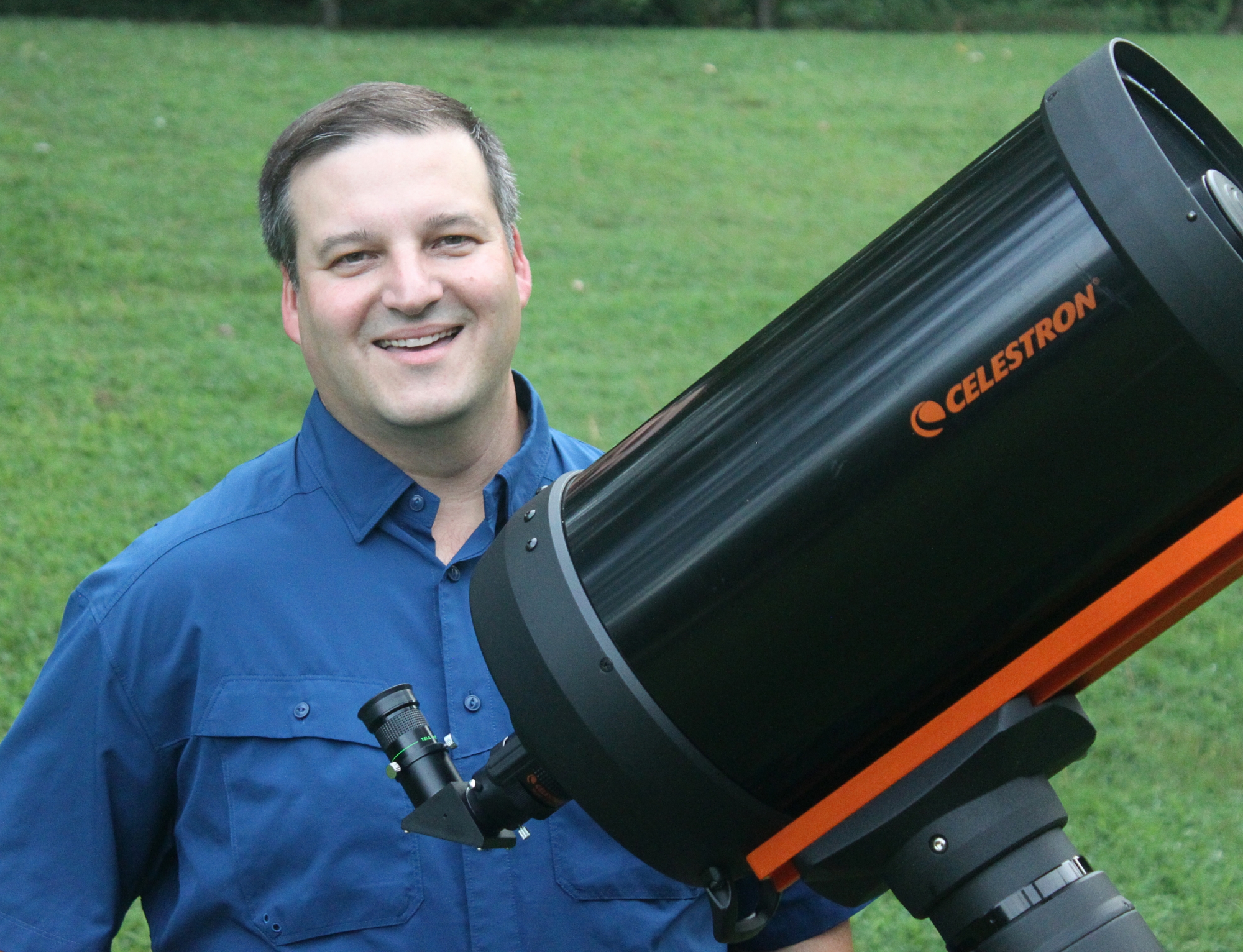 Photo of Greg Revera standing with a telescope