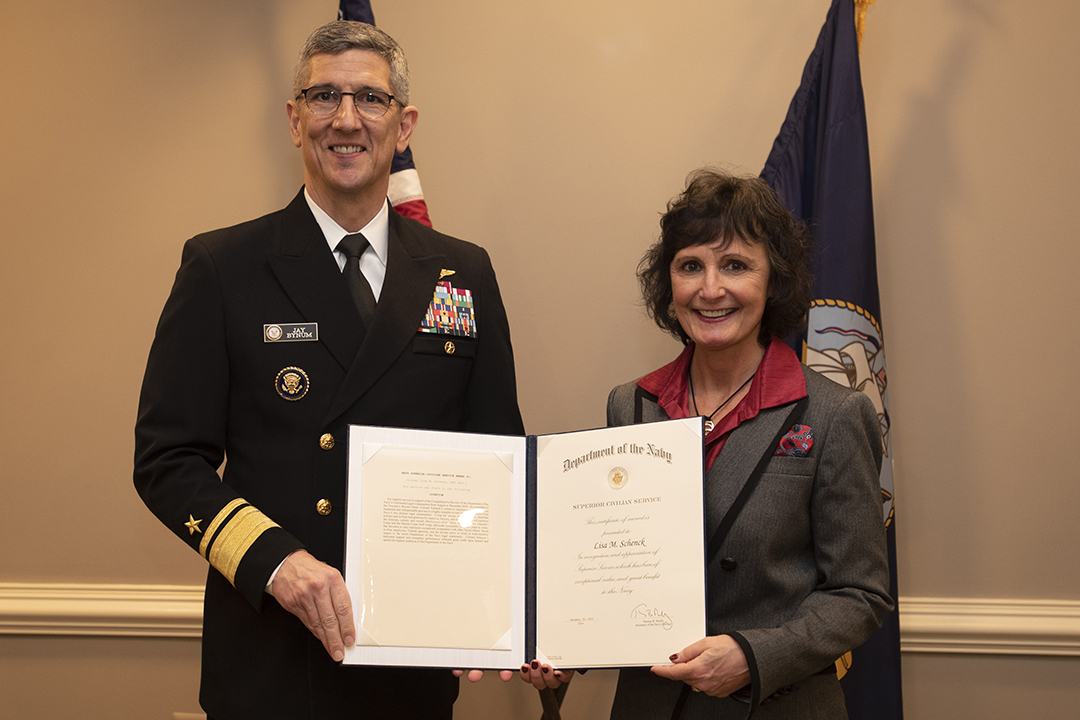 Associate Dean Lisa M. Schenck receives an award from Rear Admiral (Upper Half) Jay Bynum. 