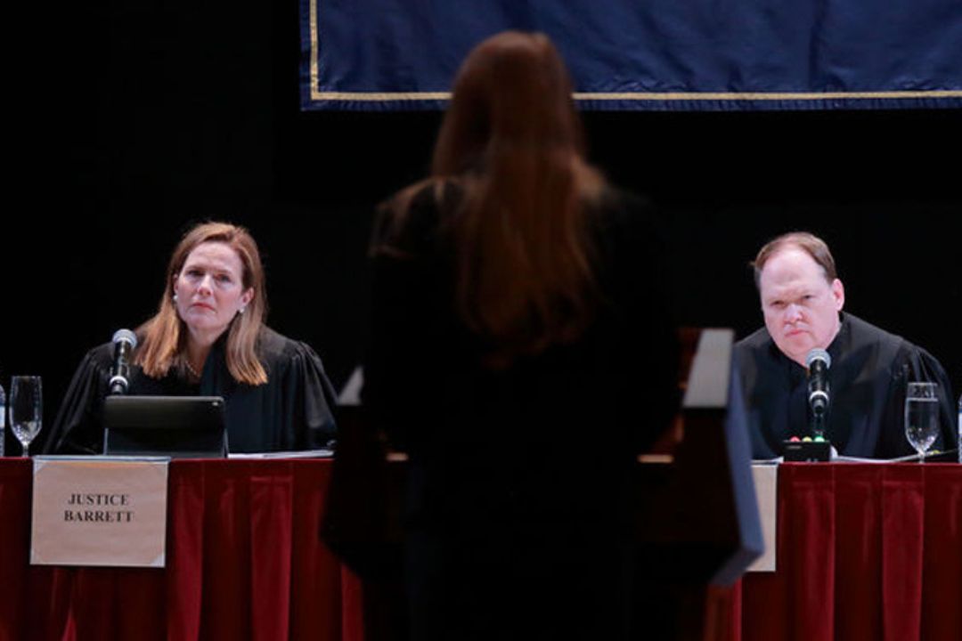 Skills competition; someone presenting as the judges, including Justice Barrett, watch