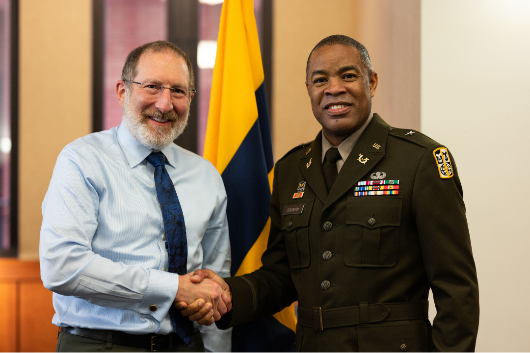 Two men shaking hands and looking at the camera smiling