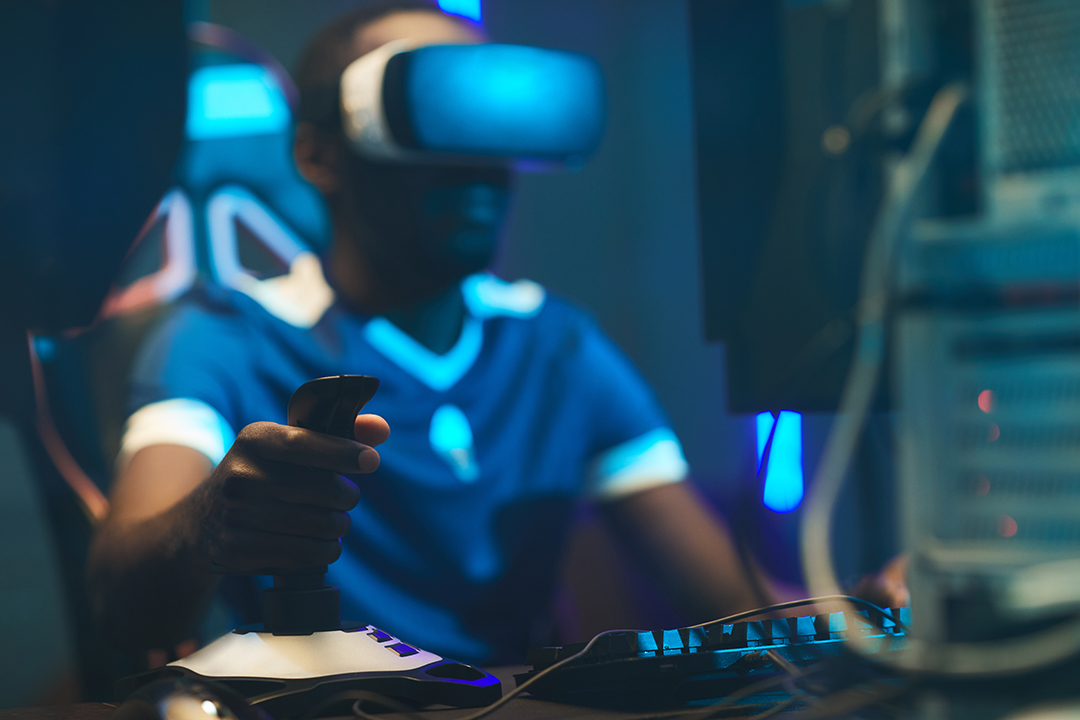 Person playing an esports game with alternate reality glasses in front of a computer.