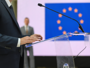 Politician speaking at a political rally, European Union flag in background
