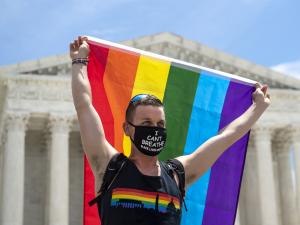 Joseph Fons hold up Pride Flag in front of Supreme Court of United States