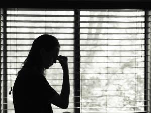 Upset woman standing in front of a window.