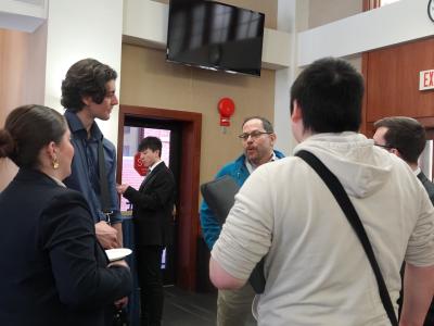 A group of students talk to a professor at the Adjunct Professor networking event.