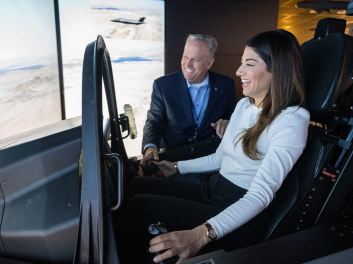 A student learning how to fly the aircraft simulator with an instructor helping her