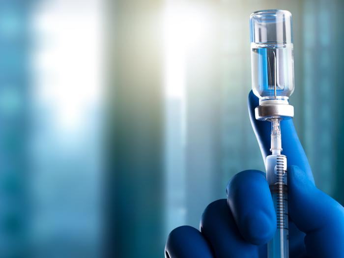 Blue gloved hand holding a syringe