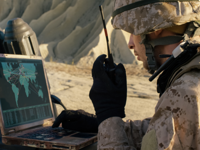 Soldier Using Laptop Computer and Radio for Communication During Military Operation in the Desert.