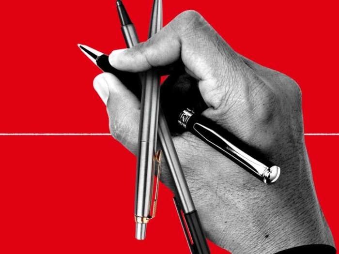 a hand holding three pens