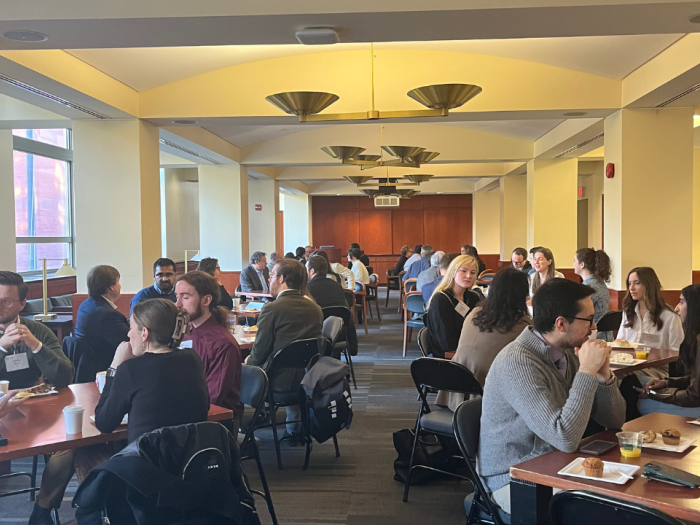 Students and alumni sitting at tables talking and eating pastries