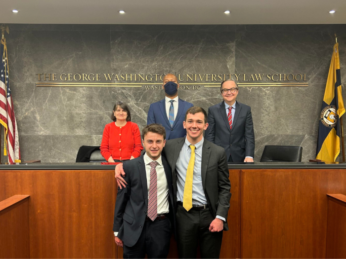 Jane Drummey, Judge Charles Thomas, and Judge Jeffrey Smith on the bench with students Kyle Coopersmith and James Dugan after winning the competition