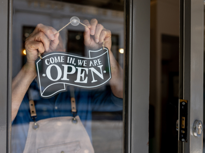 Close-up on a business owner hanging an open sign on the door of his restaurant
