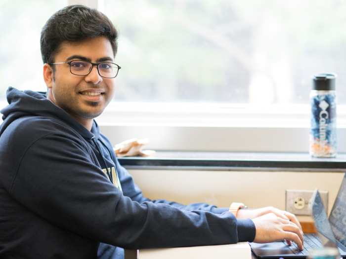 A male student looking at the camera and typing