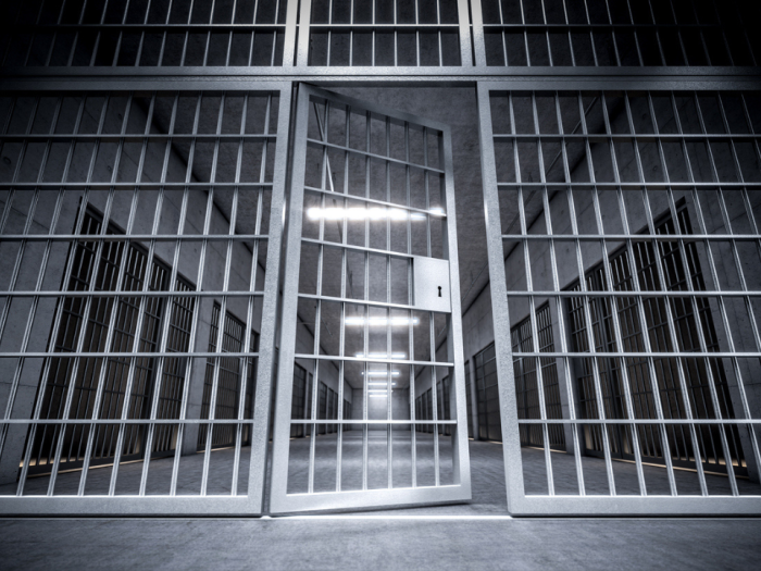 corridor of a prison with bars and open cell door