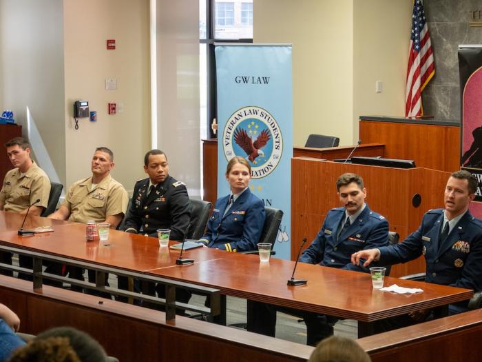 Six JAG Corps members wearing military uniforms and sitting at a table answer law students' questions during the annual JAG recruiter panel event.