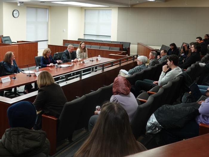 Students listen to a panel of professors in the Burns Moot Court Room.