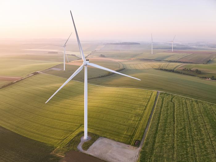 Wind turbines on a farm field during sunrise.