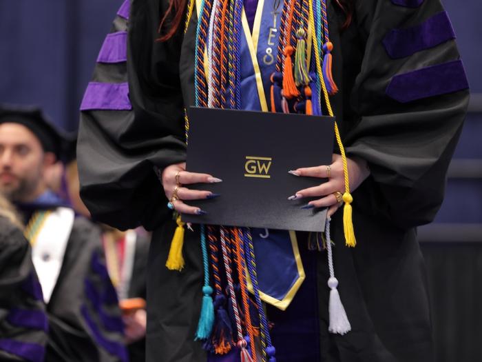 A Gw Law student carries her diploma during graduation.