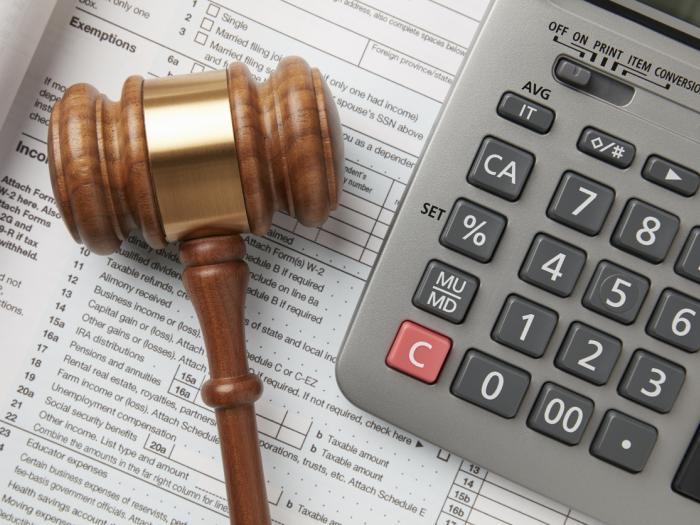 A stock image of a gavel on a tax form next to a calculator